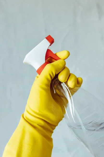 about-us-02 Hands in yellow gloves wiping a wall with a sponge and spray bottle.